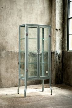 an empty glass cabinet sitting in front of a wall with no one standing inside it