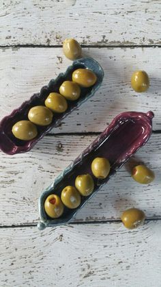 two ceramic containers filled with olives on top of a wooden table