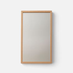 a wooden frame mirror mounted on the wall with a white back ground and light wood trim