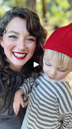 a woman holding a child wearing a red hat