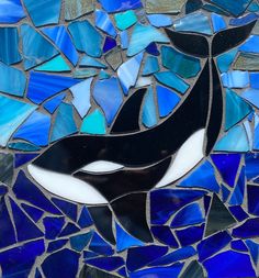 an orca killer whale is depicted in this mosaic glass paneled wall art piece