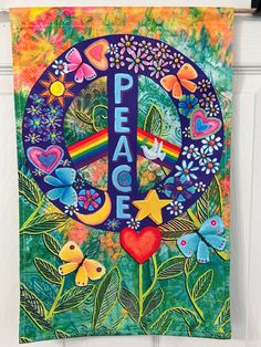 a peace sign hanging on the side of a white door with flowers and butterflies around it