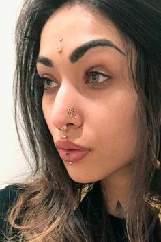 a close up of a person with piercings on her nose and nose ring in front of their face