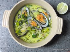 a bowl filled with soup next to a lemon wedge