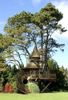 a tree house built into the side of a green field with trees in the background