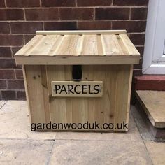 a wooden box sitting on the ground next to a brick wall with words parcells written on it