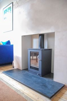 a living room with a blue couch and a wood burning stove in the middle of it