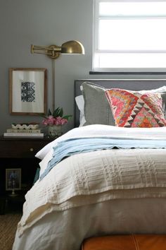 a bed with pillows and blankets on top of it next to a window in a bedroom