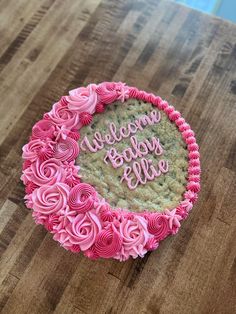 a cookie decorated with pink icing on top of a wooden table