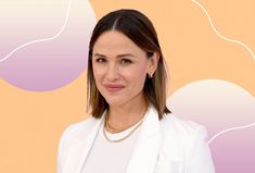 a woman in a white suit and necklace standing with her arms crossed, looking at the camera