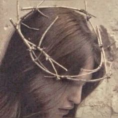 a woman wearing a crown of branches on her head with the word jesus written in it