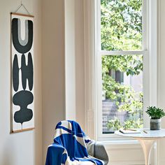 a living room with a chair, table and large painting on the wall next to it