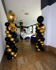 black and gold balloons in the shape of roses are on display at an event with tables set up behind them