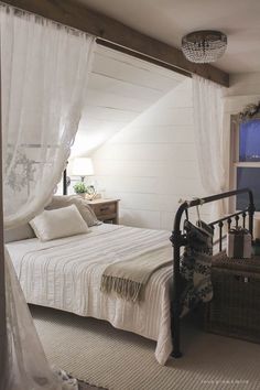 a bedroom with white walls and curtains on the windowsills is pictured in this image