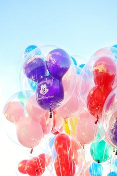 a bunch of balloons that are floating in the air with disney mouse ears on them