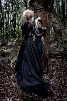 two women dressed in black are looking into a mirror