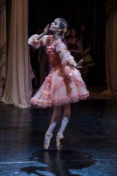 the ballerina is dressed in pink and white