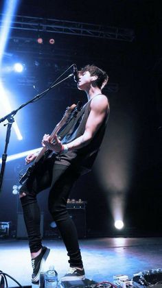 a man standing on top of a stage with a guitar in front of his face