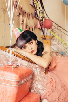 a woman laying on top of a bed next to two suitcases and a balloon