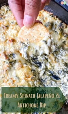 a hand dipping a piece of bread into a casserole dish with creamy spinach jalapeno and artichoke dip