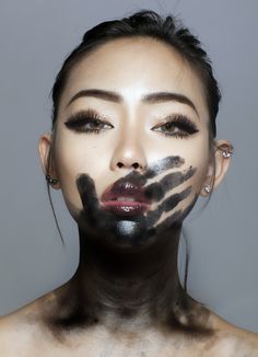 a woman with black and white makeup on her face is looking at the camera while she has hands painted all over her face