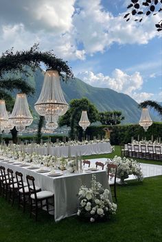 an outdoor wedding setup with chandeliers and tables set up for the guests to eat