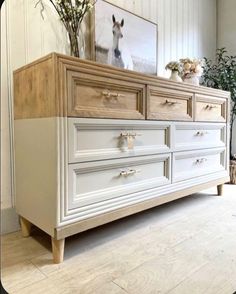 a white dresser with drawers and flowers on top