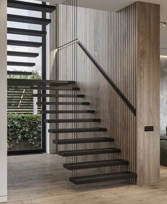 a modern staircase with black handrails and wood paneling on the wall behind it