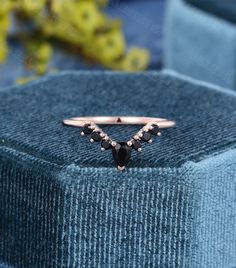 a black diamond ring sitting on top of a blue velvet box with flowers in the background