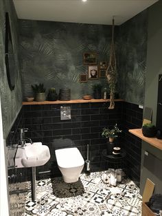 a black and white tiled bathroom with plants on the shelf above the toilet, sink and mirror