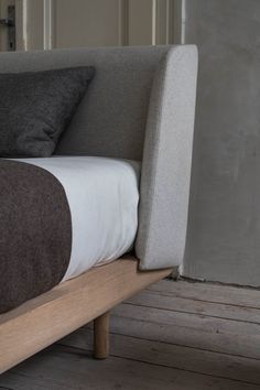 a bed with two pillows on top of it and a wooden foot board in front of the headboard