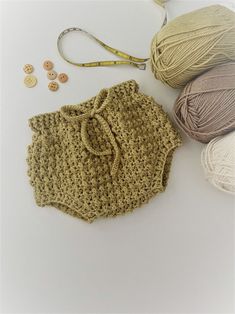 several balls of yarn and crochet on a white surface next to two skeins of yarn