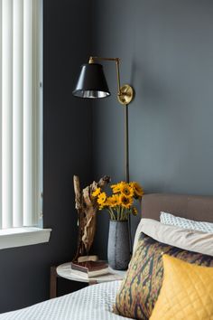 a bed room with a neatly made bed and a lamp on the nightstand next to it