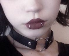 a close up of a person wearing a choker and piercings on her lips