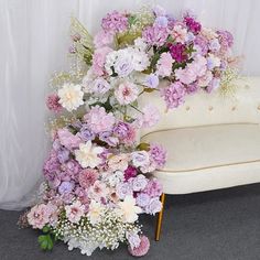 a white couch sitting next to a bunch of flowers on top of a carpeted floor