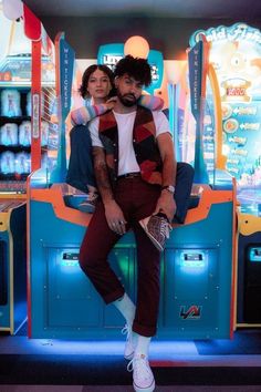 a man and woman sitting on top of each other in front of a carnival machine