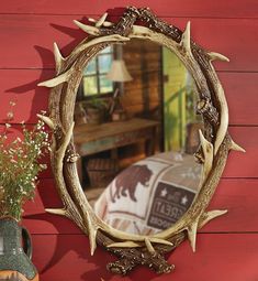 a mirror hanging on the side of a red wall next to a potted plant