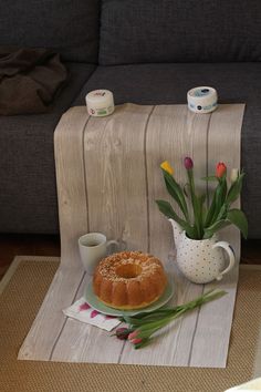 a table topped with a bundt cake next to a vase filled with tulips