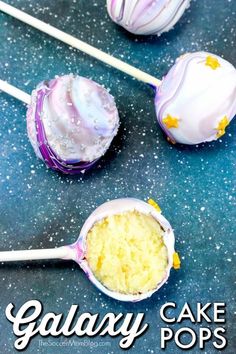 galaxy cake pops with white frosting and yellow sprinkles are on a blue surface