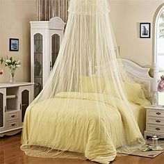 a bed with a white canopy over it in a bedroom next to a dresser and window