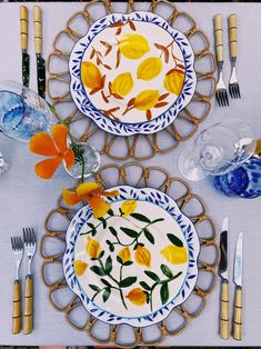 two plates with yellow flowers on them are sitting on a place mat next to silverware