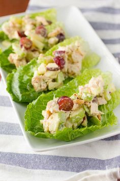 three lettuce cups filled with chicken salad on top of a striped table cloth