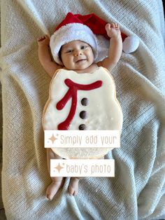 a baby laying on top of a bed wearing a santa hat and holding a cookie