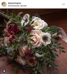 a bridal bouquet with white, red and green flowers on a wooden table top