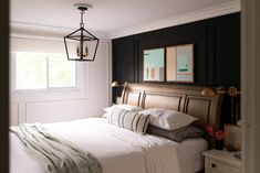 a bed with white sheets and pillows in a bedroom next to a lamp hanging from the ceiling