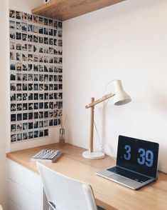 a laptop computer sitting on top of a wooden desk in front of a wall covered with photos