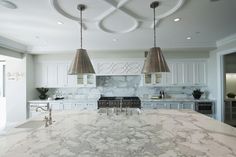 a kitchen with marble counter tops and two pendant lights hanging from the ceiling above it