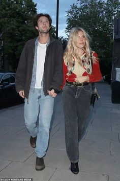 the man and woman are walking down the sidewalk together, both carrying their hand in each other's pockets