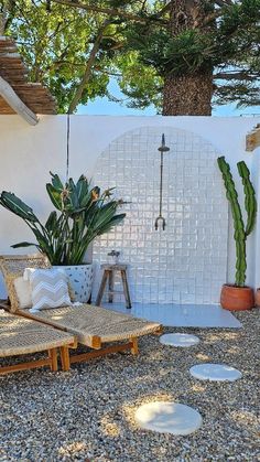 an outdoor patio with plants and potted plants on the side of the house, surrounded by gravel