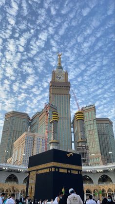 the ka'bah in front of some tall buildings under a cloudy blue sky